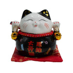 Close-up of black ceramic money cat bank painted symbols and bells